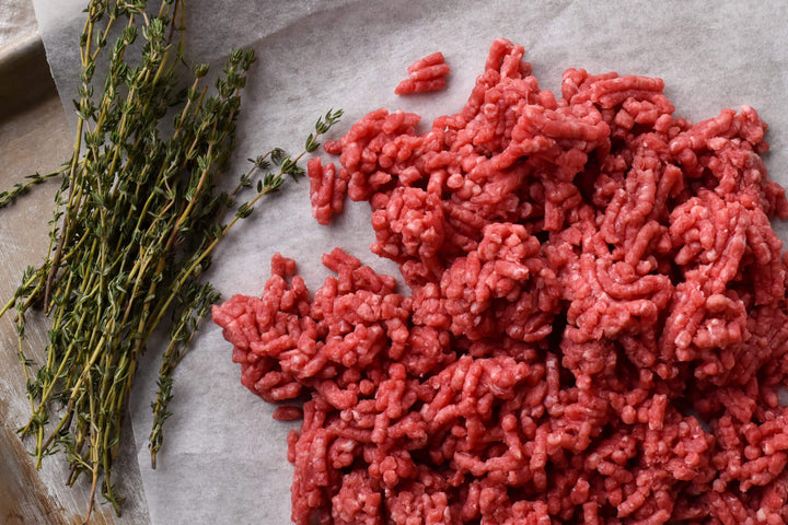 Vacuum-sealed pound of Blackwater pasture-raised ground beef on a wooden board.